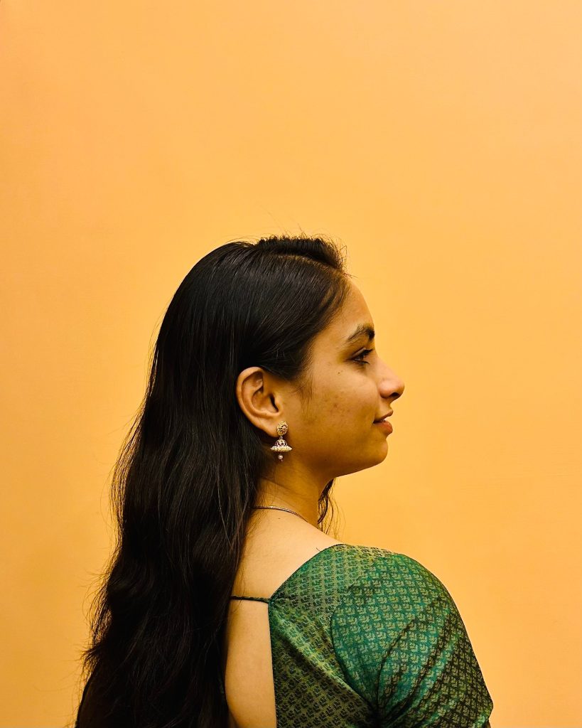pexels-photo-20876540-20876540 Elegant side profile of a South Asian woman in a green sari against a warm background.